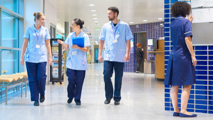 Three young NHS professionals walking through a hospital corridor.