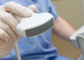 A person in scrubs holds an ultrasound wand