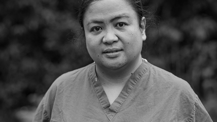 A black and white image of a woman with dark hair wearing scrubs.