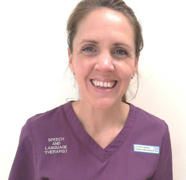 A woman in purple scrubs smiles for the camera