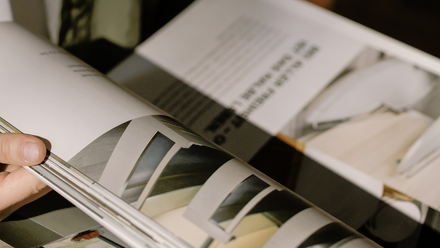 A person's hand flicking through a magazine which is open
