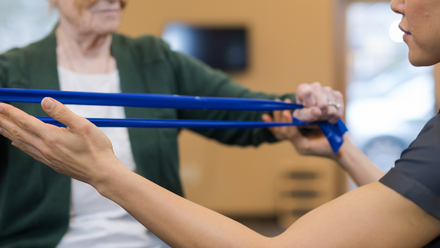 An older woman complete physiotherapy with a blue resistance band